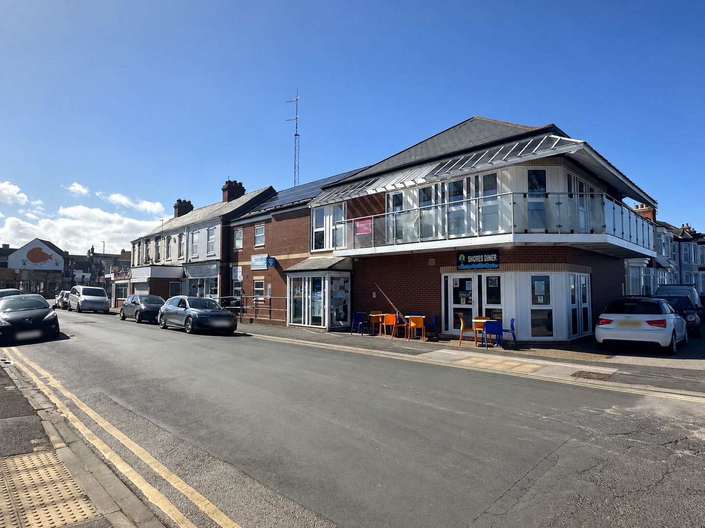 The Shores Centre Building is a 2 story brick building with white windows and a balcony on the first floor